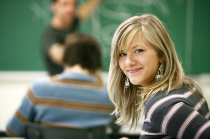 student smiling looking back at camera while instructor teaches.