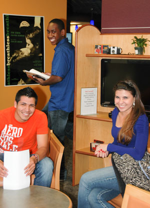 three students smiling in library